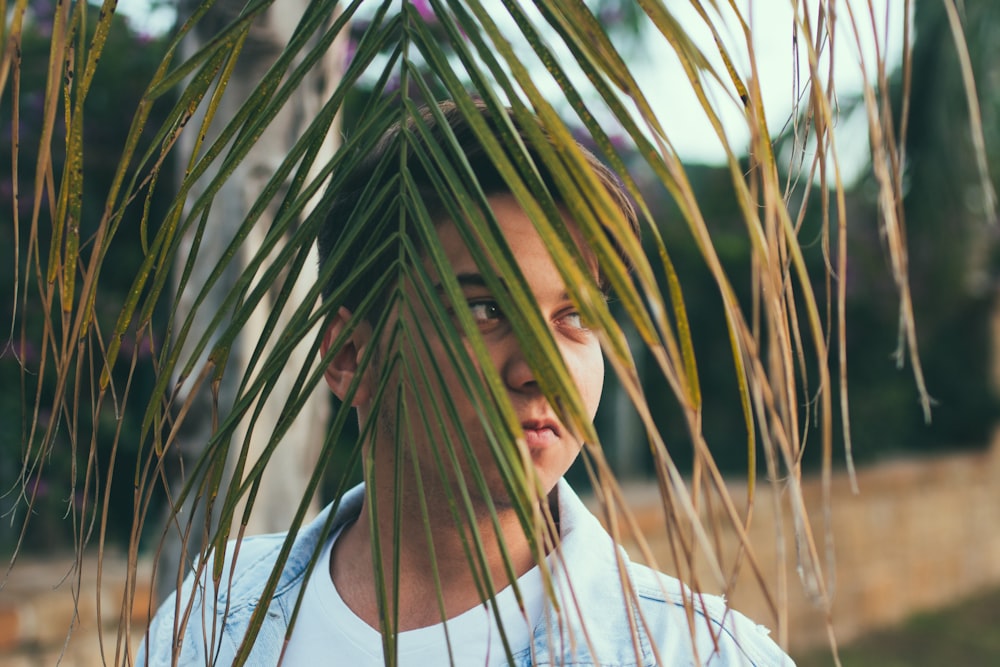 man covering his face with coconut leaves