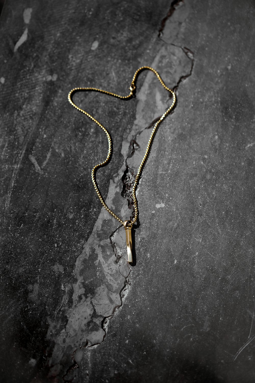 brown and grey necklace with pendant in a grey surface close-up photography