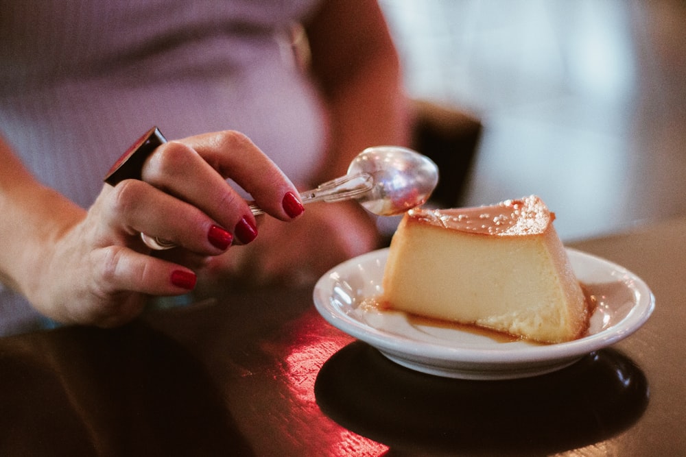 person holding spoon about to slice dessert