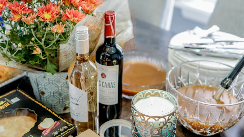 a table topped with bottles of wine and a bowl of food