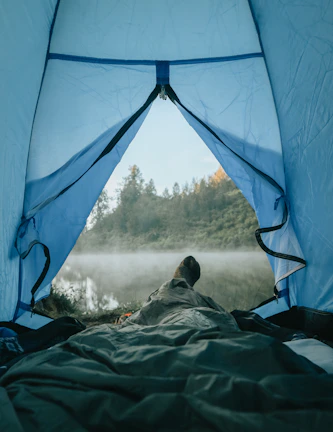 A misty morning view of a tent pitched beside a serene alpine lake in the Canadian Rockies