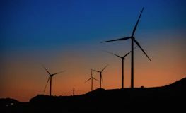 Wind turbines spinning under a twilight sky with digital overlays showing real-time AI adjustments.