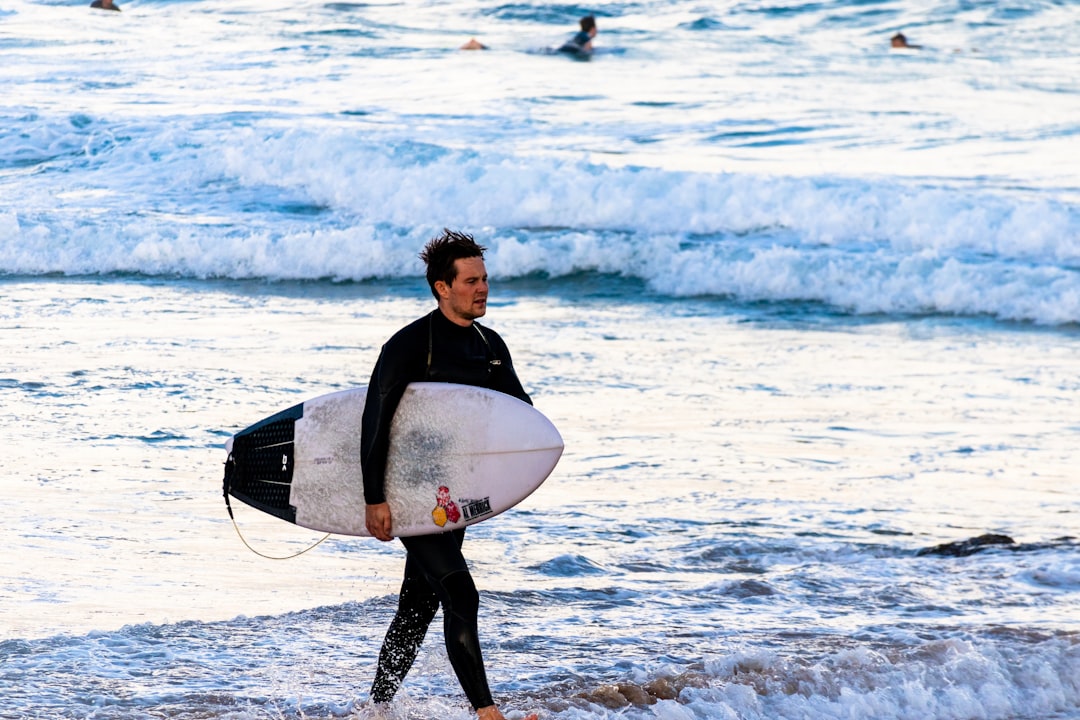 man walking on seashore with surfboard