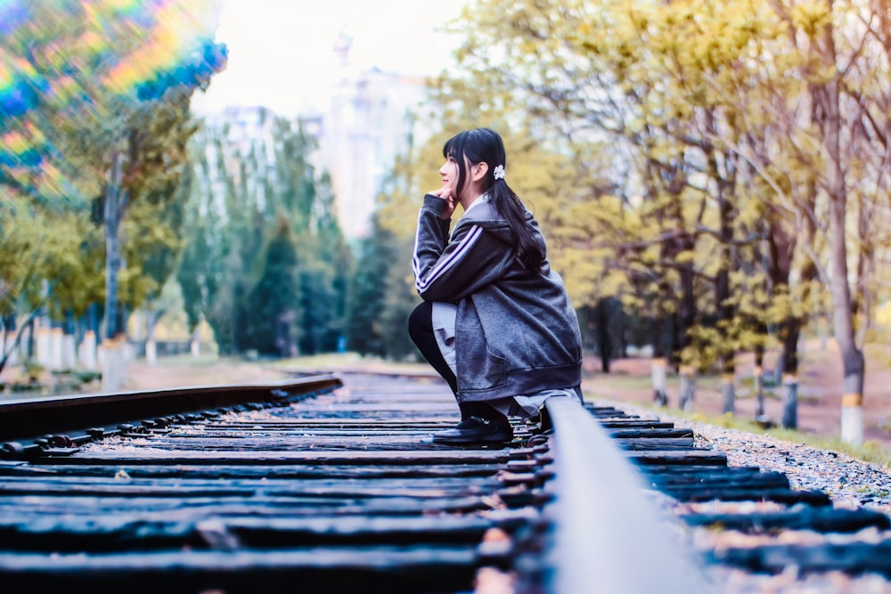 woman sitting on pavement near tall trees