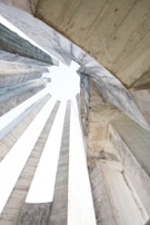 Concrete structures with a modern architectural design create vertical columns converging towards the sky, forming an abstract geometric pattern.