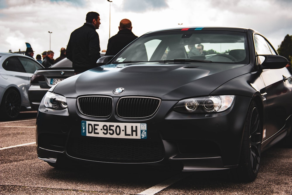 two men standing beside black BMW sedan