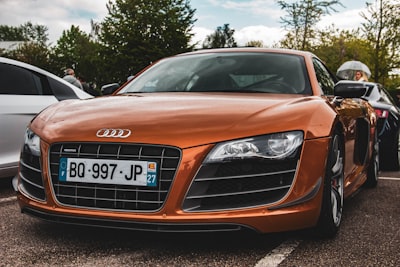 orange audi car parked beside car super teams background