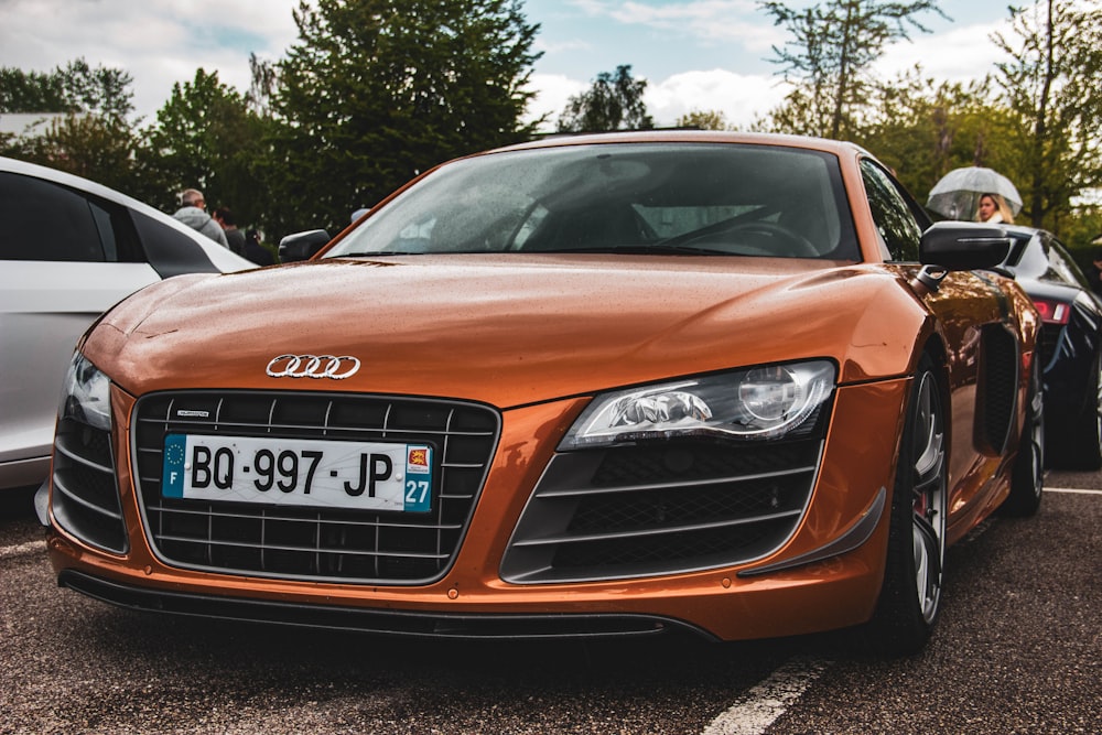 orange Audi car parked beside car