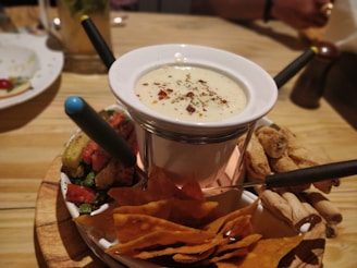 white fondue pot with chips on table