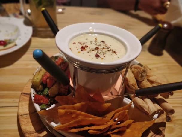 white fondue pot with chips on table