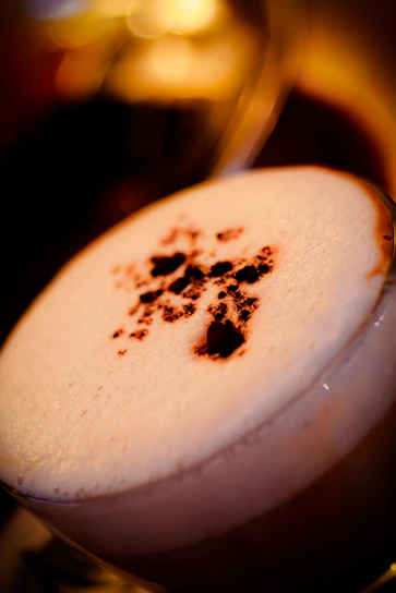 Close-up of a frothy gold coffee frappe topped with whipped cream and a sprinkle of cinnamon.