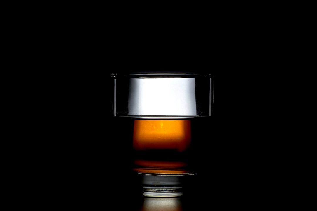 clear shot glass, A clean glass of whiskey alcohol with lighting behind it and a reflection on the ground.