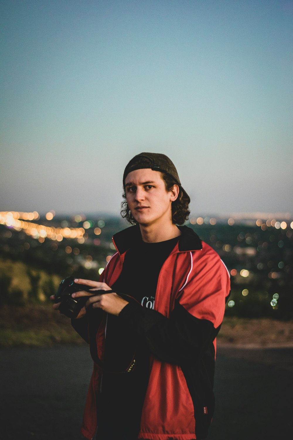 man wearing red and black zip-up jacket standing outdoor during daytime