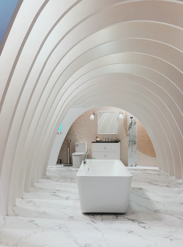 White bathroom of repeating arches over a marble floor and a bathtub