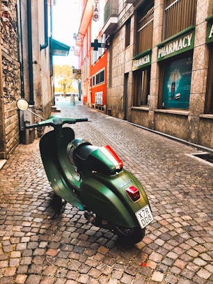 green motor scooter parked beside building