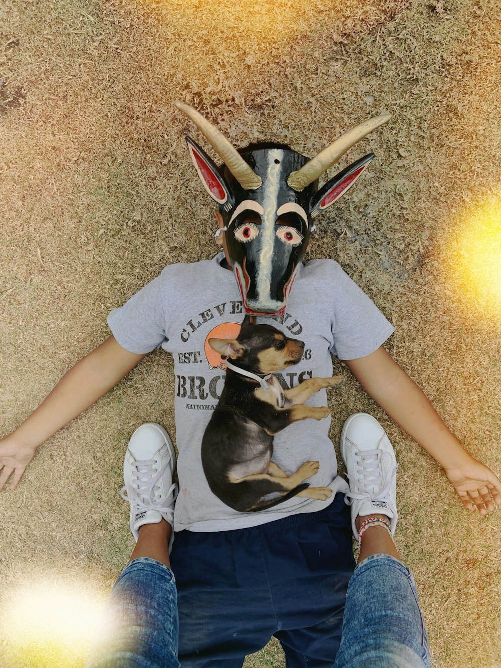 persons standing on boy lying on ground with dog on