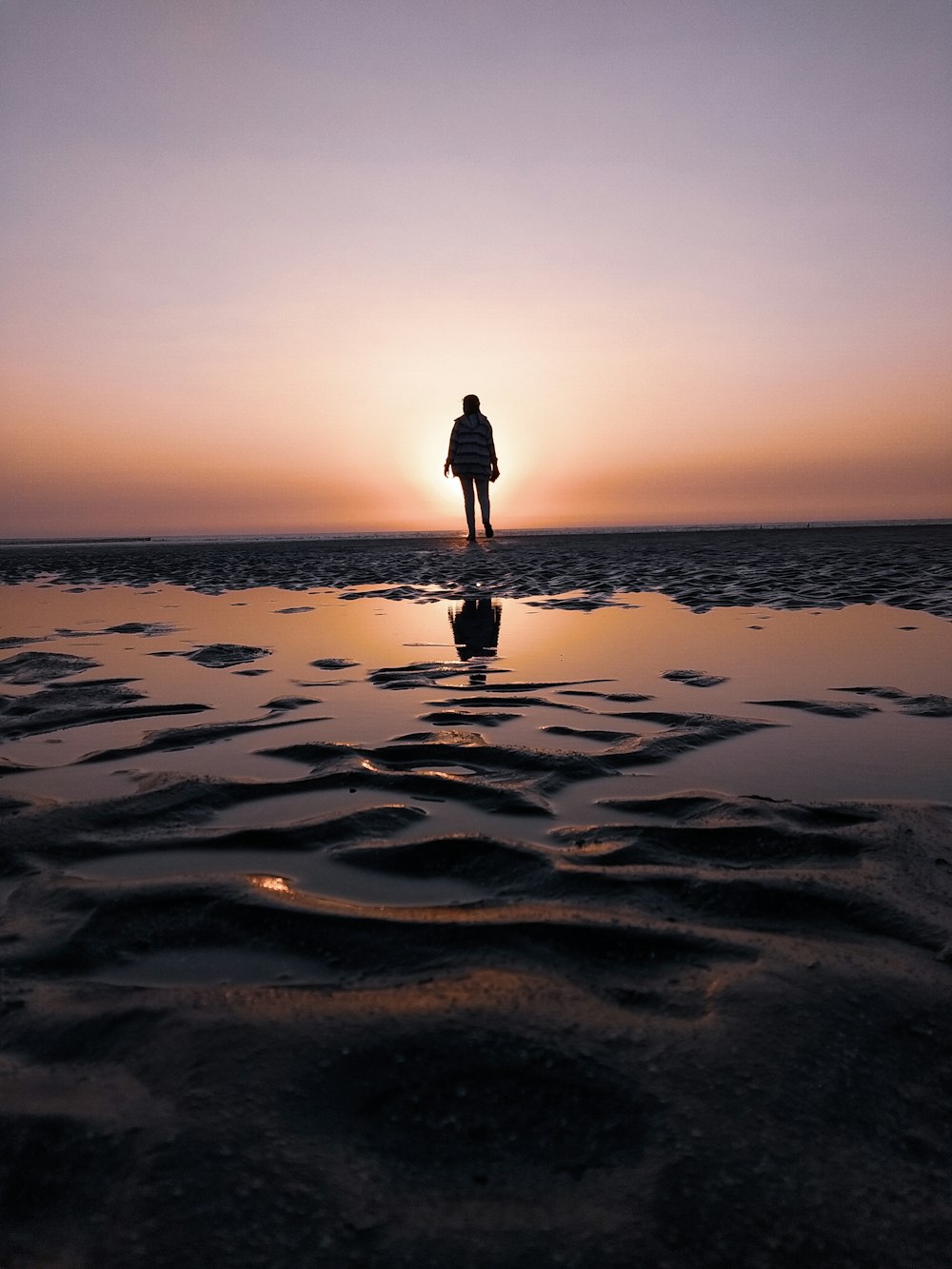 person walking on beach during sunset