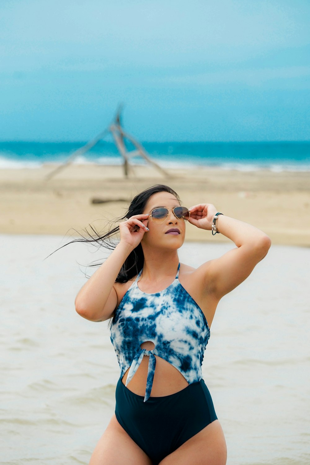 femme en bikini noir et bleu debout sur le bord de mer pendant la journée