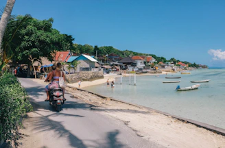 A happy rider cruising a colorful scooter along a coastal road with turquoise waters.