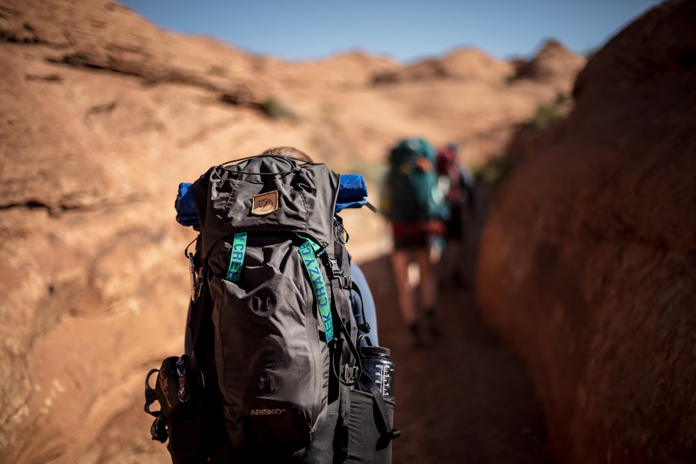 selective photo of person walking and carrying hiking backpack during daytime