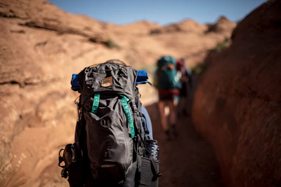 selective photo of person walking and carrying hiking backpack during daytime