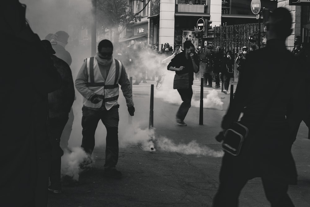 Photo en niveaux de gris de personnes à proximité de la fumée