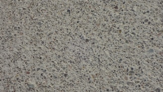 A close-up view of a textured concrete surface with small stones embedded, creating a speckled appearance.