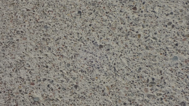 A close-up view of a textured concrete surface with small stones embedded, creating a speckled appearance.