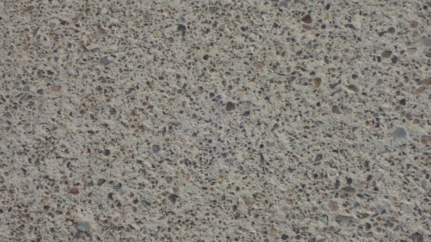 A close-up view of a textured concrete surface with small stones embedded, creating a speckled appearance.