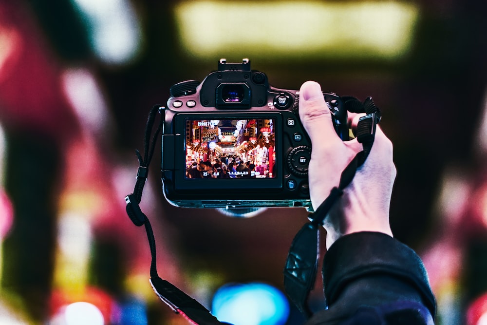 pessoa segurando câmera DSLR preta