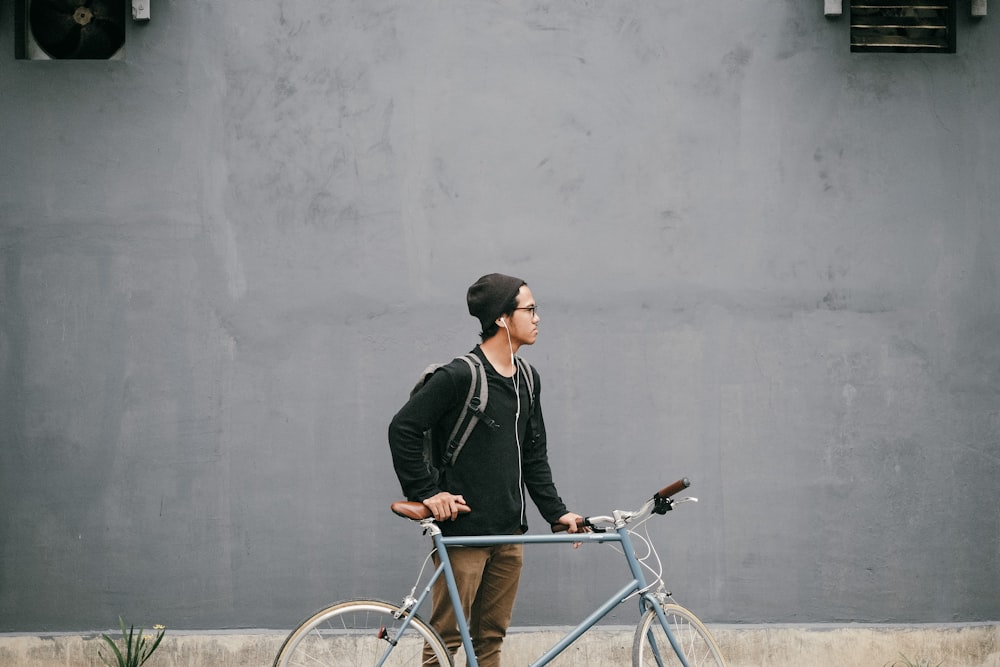 man standing and holding near gray fixie bike