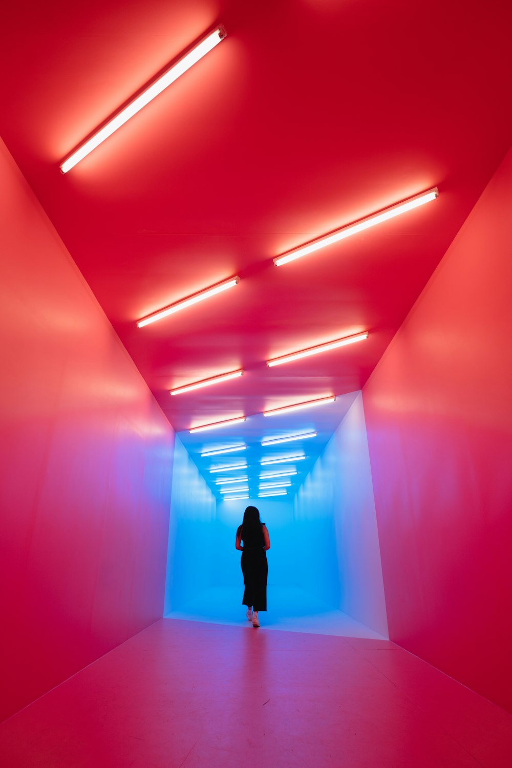 woman in black dress standing between pink walls