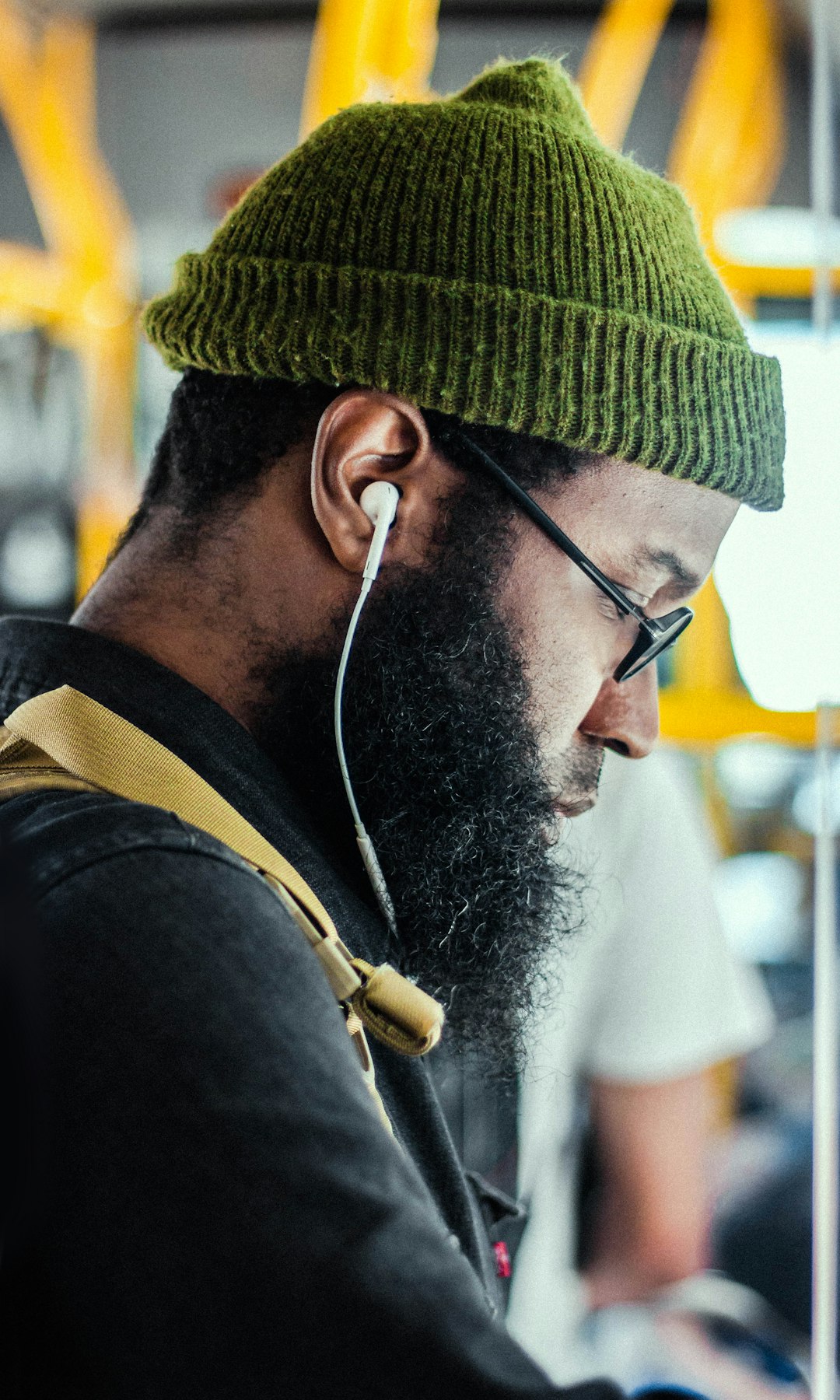 man wearing green knit cap using Apple EarPods