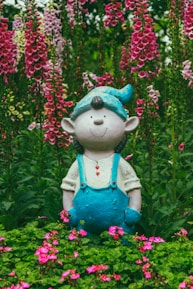 A cheerful gnome statue nestled among blooming plants in a sunny garden.