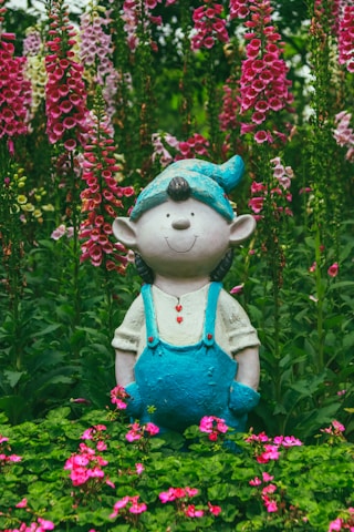 A cheerful gnome statue nestled among blooming plants in a sunny garden.