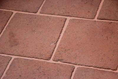 Close-up of a rustic terracotta floor tile with natural texture and warm tones.