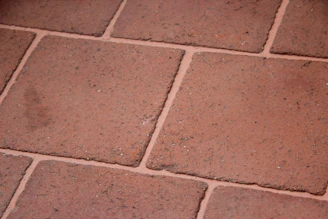 Close-up of skilled hands laying elegant Mediterranean-style tiles on a sunlit terrace.