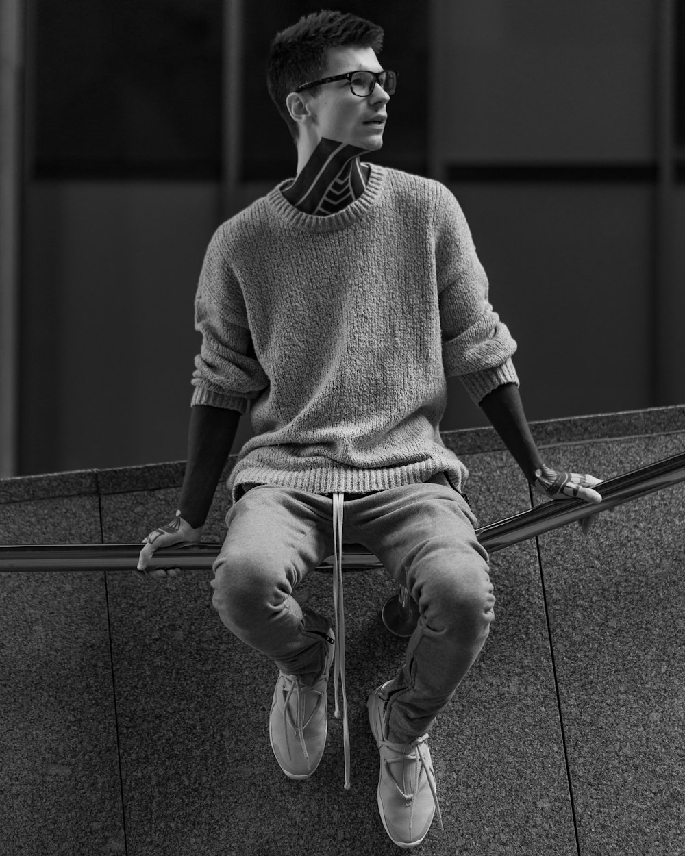 man in sweater sitting on railings
