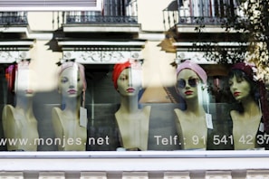Fashionable hats displayed on mannequin heads in a bright store corner.
