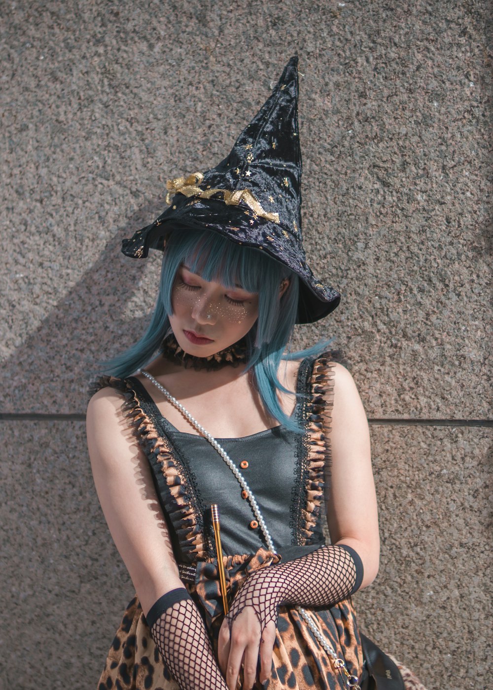 woman wearing witch costume leaning on gray wall