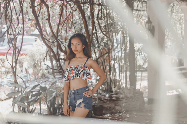Young woman in stylish jeans and a cropped top laughing while walking through a lavender garden.