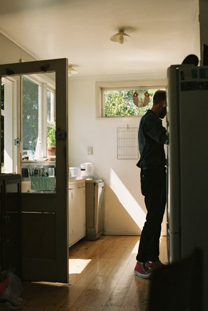 Craftsman measuring kitchen space with natural light pouring in from a window