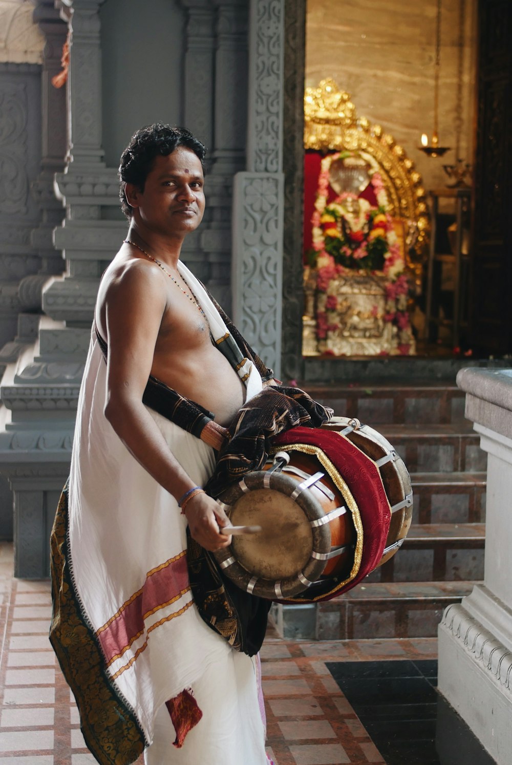 man wearing white dress holding musical drum