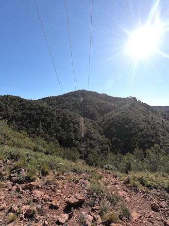 An expansive transmission line stretching over lush green hills under a clear blue sky.