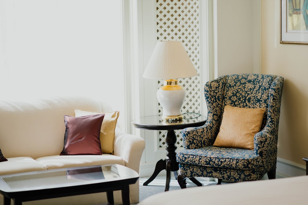 white and gold table lamp on round table in between sofa chair and sofa