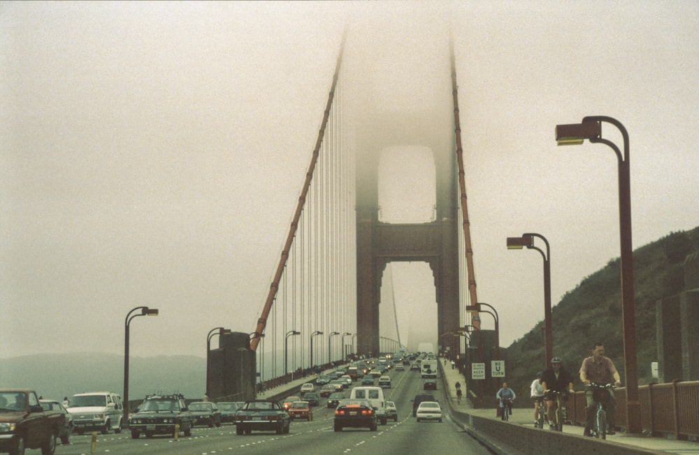 cars travelling on Golden Gate bridge covered in grey fogs