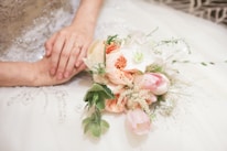 Close-up of wedding rings resting on a delicate lace handkerchief beside a bouquet of wildflowers.