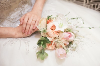 Close-up of wedding rings resting on a delicate lace handkerchief beside a bouquet of wildflowers.
