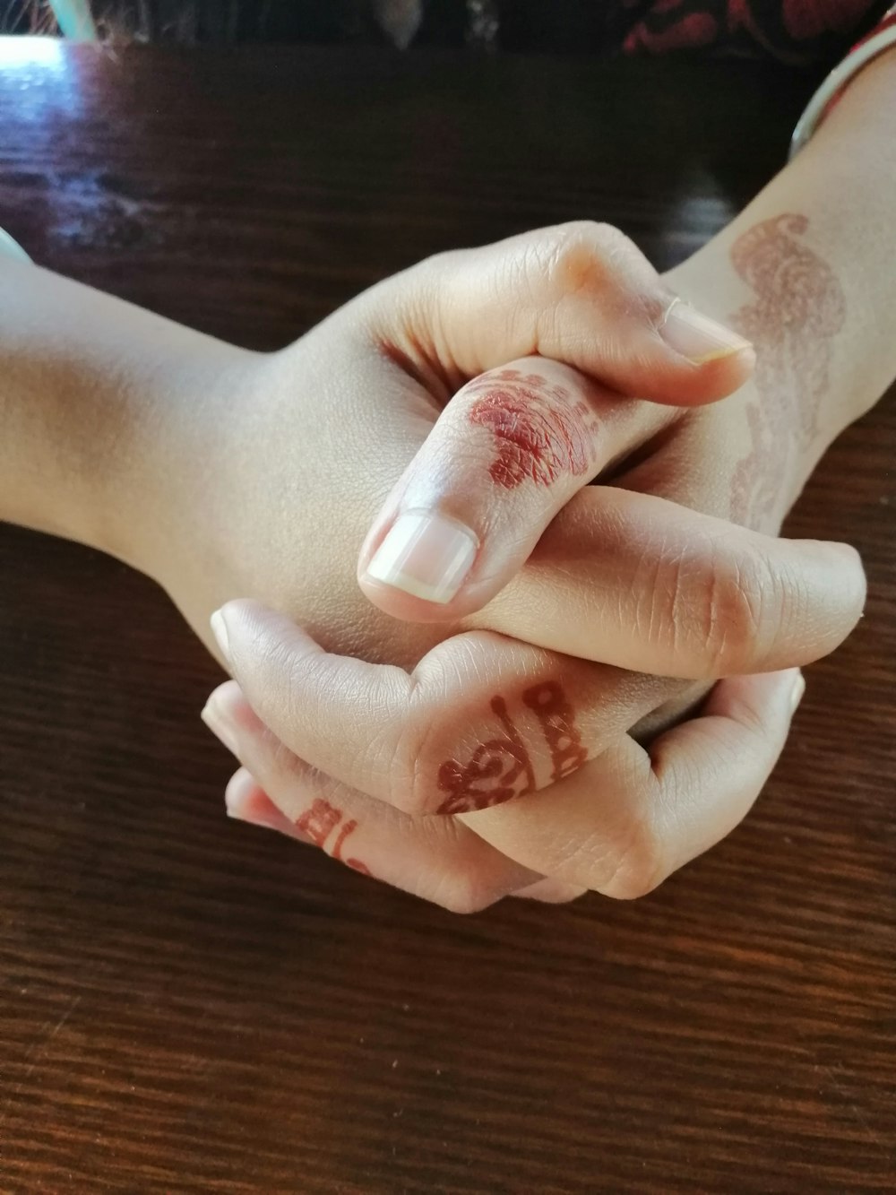 person's hands with red mehndi tattoos