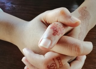 person's hands with red mehndi tattoos